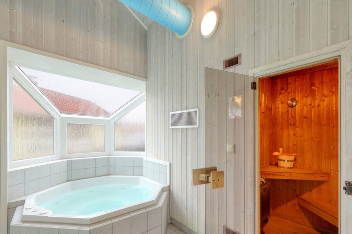A bathroom with a freestanding bathtub, a skylight, and a wooden sauna area.
