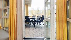 A room with a sliding glass door leading to an outdoor deck with a table and chairs. - 4 Star Holiday Home in Ottendorf (Otterndorf)