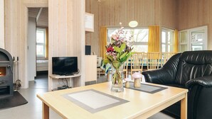 A living room with a fireplace, a television, a dining area with yellow curtains, and a black leather sofa. - 4 Star Holiday Home in Ottendorf (Otterndorf)