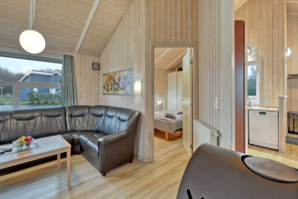 A modern interior with a leather sofa, a dining table, and a kitchen area.
