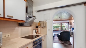 A kitchen with a built-in oven, a stainless steel range hood, and a window overlooking a patio area. - Apartment 'Hohenstein' with Mountain View, Private Terrace and Wi-Fi (Willingen (Upland))