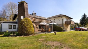 A two-story house with a brick chimney, a satellite dish, and a covered patio with chairs. - Apartment 'Hohenstein' with Mountain View, Private Terrace and Wi-Fi (Willingen (Upland))