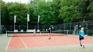 Cancha de tenis exterior con red, rodeada de árboles.