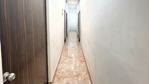Käytävä, jossa on marmorilattia, vasemmalla puolella puinen ovi ja oikealla puolella valkoinen seinä.