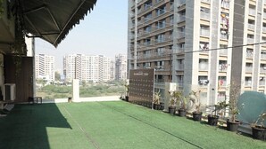 A rooftop terrace with artificial grass, potted plants, and a sign for Hotel Elegant Inn. - Hotel Elegant inn (Surat)