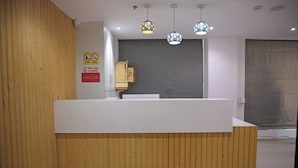 A reception desk with a wooden finish, a sign prohibiting outside food, and a no smoking sign. - Hotel Elegant inn (Surat)