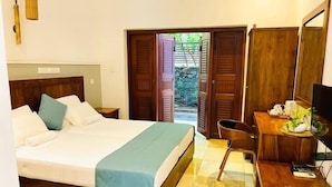 A hotel room with a bed, a desk with a chair, a television, and a wooden wardrobe.