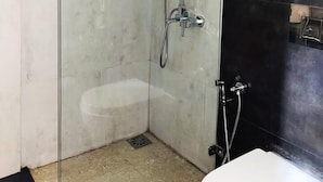 A modern bathroom with a glass-enclosed shower, a black tiled wall, and a white sink.
