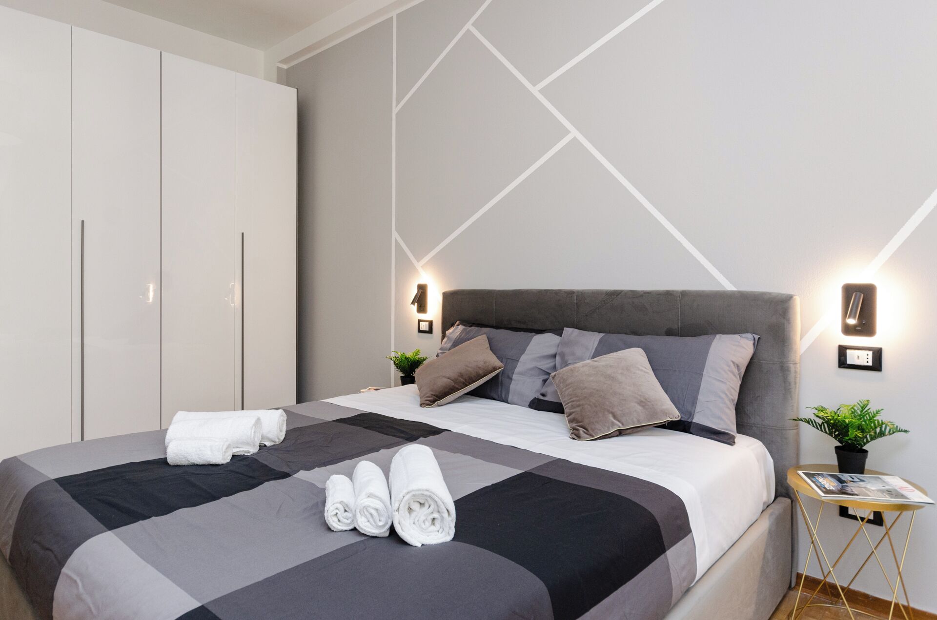Una camera da letto moderna con un letto, un armadio e un comodino con una pianta.