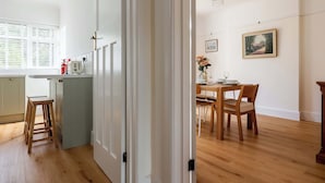 Une cuisine moderne avec une fenêtre, un coin repas comprenant une table et des chaises, et un tableau accroché au mur.
