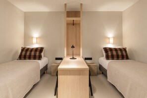 Una habitación de hotel con dos camas, una mesita central y lámparas de noche.
