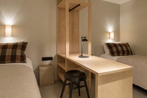 Una habitación de hotel con una cama individual, un escritorio, una silla y un armario.