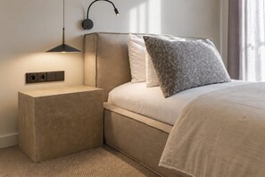 Ein modernes Schlafzimmer mit Bett, Nachttisch und Wandlampe.