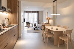 Una cocina moderna con armarios de madera, un comedor con una mesa redonda y sillas, y una sala de estar con un sofá y una mesa de centro.