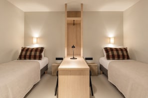 Una habitación de hotel con dos camas, una mesita central y lámparas de noche.