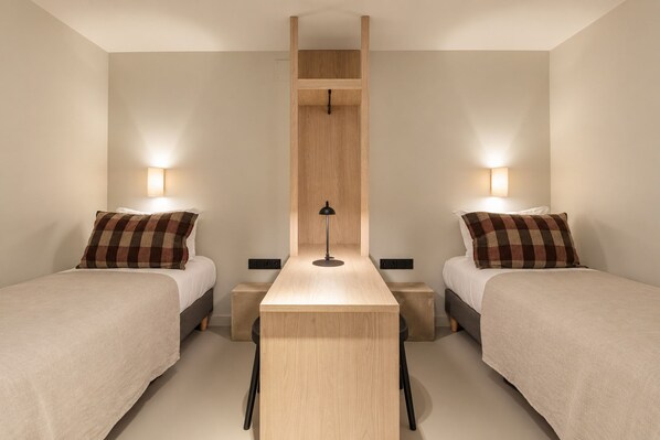 A hotel room with two beds, a central table, and bedside lamps.