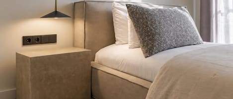 Un dormitorio moderno con cama, mesita de noche y lámpara de pared.