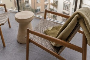 A balcony with wicker furniture, including a chair and a round table.