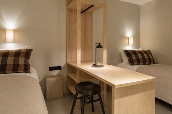 A hotel room with a single bed, a desk, a chair, and a wardrobe.