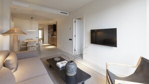 Ein modernes Wohnzimmer mit einer Couch, einem Couchtisch und einem an der Wand montierten Fernseher.