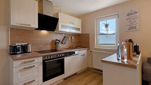 A modern kitchen with white cabinets, a wooden countertop, a built-in oven, and a window with a view. - Apartment 'Schwarzwaldliebe' with Mountain View, Private Terrace and Wi-Fi (Oberharmersbach)