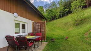 An outdoor seating area with a table and chairs, a wooden fence, and a grassy slope. - Apartment 'Schwarzwaldliebe' with Mountain View, Private Terrace and Wi-Fi (Oberharmersbach)