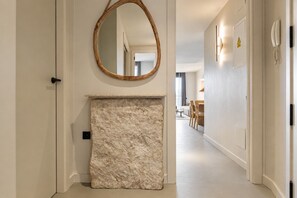 A hallway with a stone fireplace, a round mirror, and a door with a telephone.