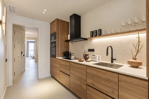 Una cocina moderna con armarios de madera, campana extractora negra, pileta doble y encimera con diversos objetos.