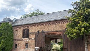 A brick building with a large wooden gate, a cobblestone entrance, and a sign indicating 'Hof Blechert.' - Apartment 'An Der Wublitz' with Shared Terrace, Shared Garden and Wi-Fi (Werder (Havel))