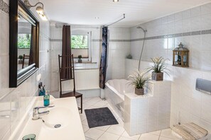 Ein Badezimmer mit Badewanne, Dusche, Waschbecken und Spiegel.