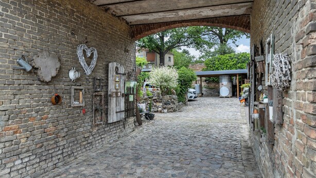 A cobblestone alleyway with brick walls, a heart-shaped decoration, and a tree in the background. - Apartment 'An Der Wublitz' with Shared Terrace, Shared Garden and Wi-Fi (Werder (Havel))
