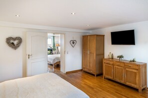 Ein Schlafzimmer mit einem Bett, einem Holzschrank und einem Fernseher an der Wand.