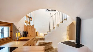 Eine moderne Küche mit einer Holzarbeitsplatte, einem eingebauten Herd und einer Treppe, die zu einem Erker führt.