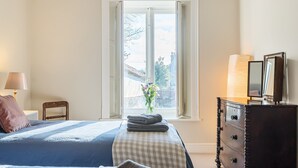 Une chambre à coucher avec un lit, une commode, une fenêtre donnant sur l’extérieur et une lampe.