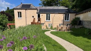 Une maison à deux étages avec un chemin de gravier menant à une terrasse en bois.
