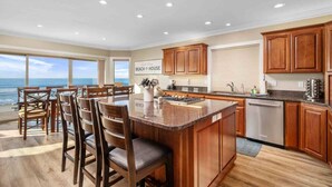 A kitchen with wooden cabinets, a central island, and a view of the ocean.