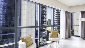 A modern living room with large windows, white furniture, and a view of high-rise buildings. - Glamorous 2BR in Damac Paramount Tower (Dubai)