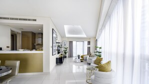 A modern living room with a sofa, coffee table, and a dining area with a table and chairs. - Glamorous 2BR in Damac Paramount Tower (Dubai)