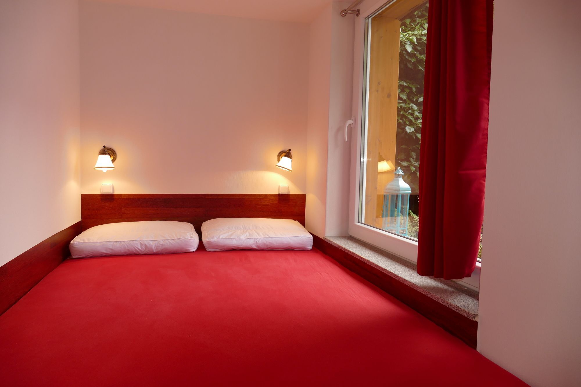 Ein Hotelzimmer mit einem Bett, zwei Wandlampen und einem Fenster mit Vorhängen.