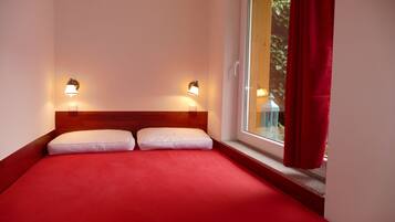 Ein Hotelzimmer mit einem Bett, zwei Wandlampen und einem Fenster mit Vorhängen.