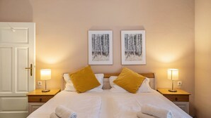 A hotel room with a double bed, two bedside tables with lamps, a door, and two framed pictures on the wall. - Room 'Doppelzimmer 3' with Mountain View and Wi-Fi (Seefeld in Tirol)