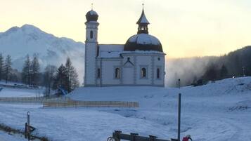Una iglesia con dos cúpulas y un campanario, rodeada por un paisaje nevado y montañas.