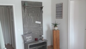 Ein modernes Interieur mit einer grauen Bank, einem kleinen Tisch mit Pflanze und einem Kronleuchter.