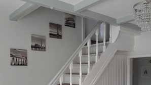 Eine Treppe mit weißen Balustraden und beige-farbenen Teppichstufen, die zu einer Zwischenebene führen.