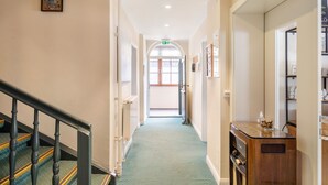 A hallway with a carpeted floor, wooden staircase, and a door at the end. - Room 14 (double room) with mountain view, balcony and Wi-Fi (Seefeld in Tirol)