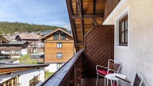 A balcony with wooden railings, a white chair, and a red cushion. - Room 14 (double room) with mountain view, balcony and Wi-Fi (Seefeld in Tirol)