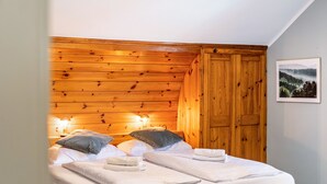 A bedroom with wooden paneling, a bed with pillows and towels, a nightstand with a lamp, and a door. - Room 14 (double room) with mountain view, balcony and Wi-Fi (Seefeld in Tirol)