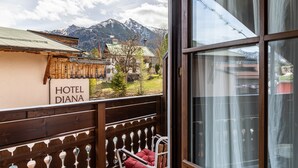 Un balcón de madera con un letrero que dice 'HOTEL DIANA', vista a las montañas y cielo despejado.