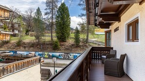 A balcony with wicker furniture, a view of a mountainous landscape, and a building with a wooden facade. - Room 4 (budget double room) with mountain view, balcony and Wi-Fi (Seefeld in Tirol)