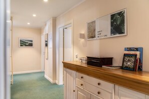 A hallway with a wooden counter, framed pictures, and a book titled 'Hunderwasser'. - Room 16 (budget double room) with mountain view, balcony and Wi-Fi (Seefeld in Tirol)